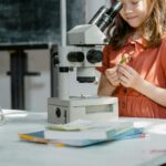 Dziewczynka ogląda preparat pod mikroskopem podczas domowego eksperymentu