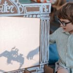 Chłopiec w okularach bawi się domowym teatrem cieni